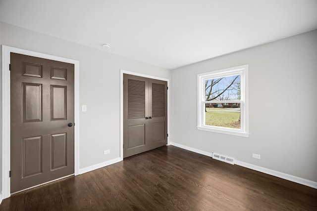 unfurnished bedroom featuring a closet and dark hardwood / wood-style floors