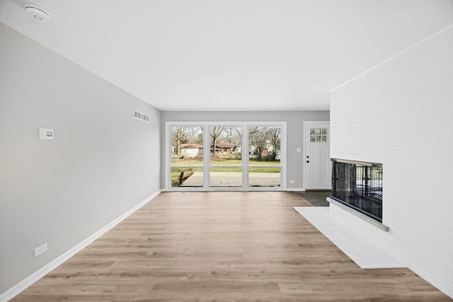 unfurnished living room featuring a multi sided fireplace and light wood-type flooring