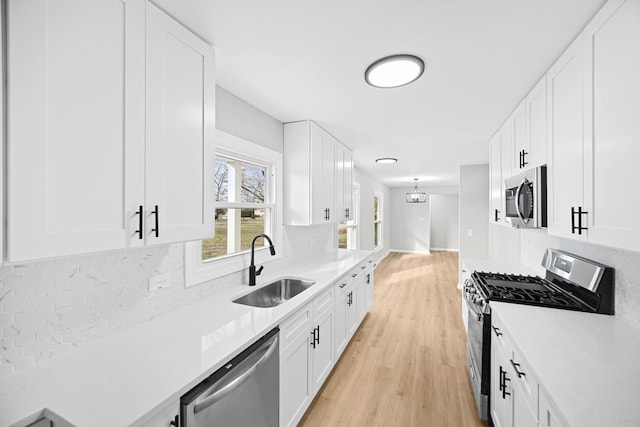 kitchen with white cabinets, light wood-type flooring, sink, and appliances with stainless steel finishes