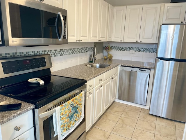 kitchen with sink, white cabinets, light tile patterned floors, and appliances with stainless steel finishes