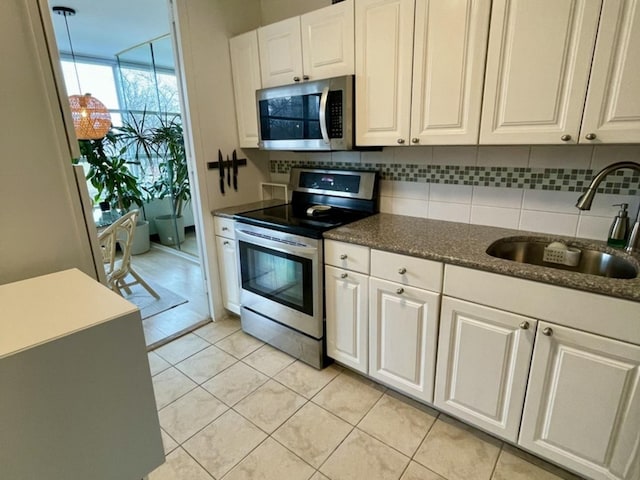 kitchen with white cabinetry, sink, decorative backsplash, light tile patterned floors, and appliances with stainless steel finishes