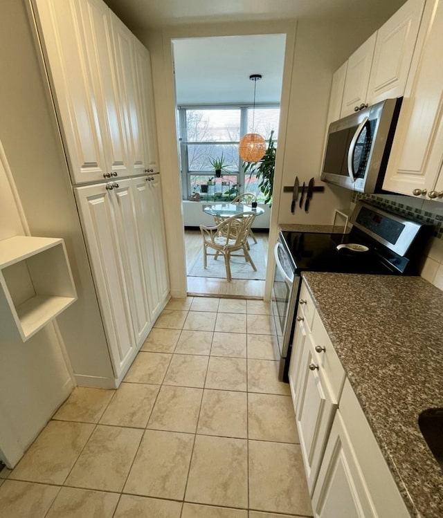 kitchen featuring light tile patterned floors, white cabinetry, appliances with stainless steel finishes, and dark stone counters