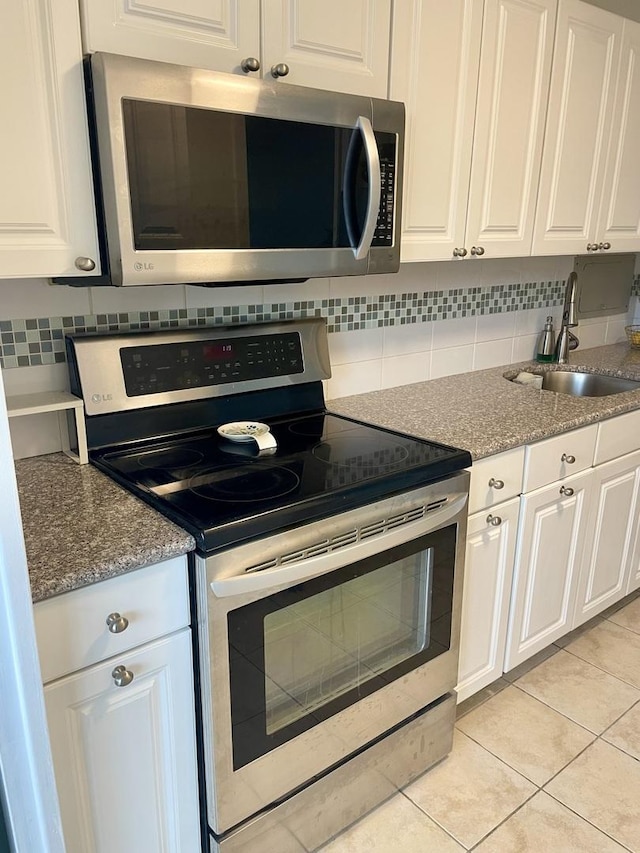 kitchen with white cabinetry, sink, light tile patterned floors, and stainless steel appliances