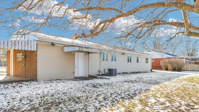 snow covered rear of property featuring cooling unit