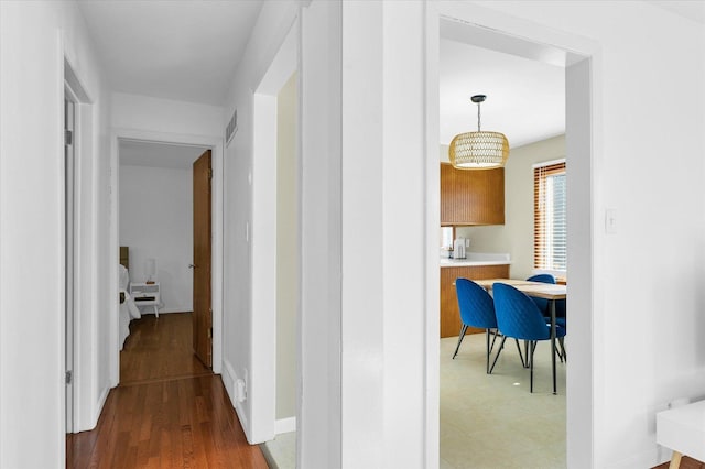 hall with wood-type flooring and an inviting chandelier