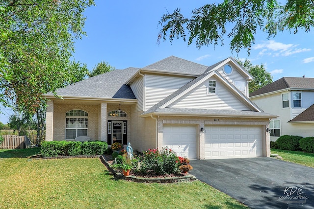 traditional-style house with driveway, brick siding, a shingled roof, fence, and a front yard