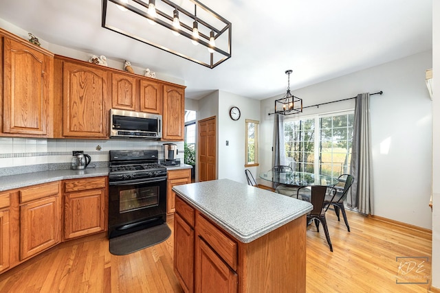 kitchen with stainless steel microwave, black gas range oven, decorative backsplash, brown cabinetry, and light wood-type flooring