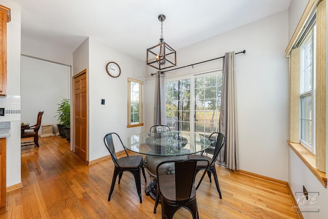 dining area featuring light wood-style floors, baseboards, and an inviting chandelier