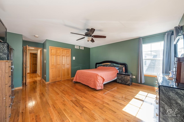 bedroom featuring light wood finished floors, baseboards, visible vents, ceiling fan, and a closet