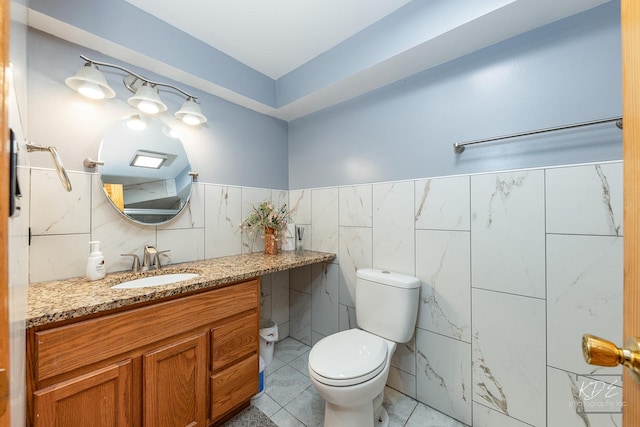 bathroom featuring toilet, tile patterned floors, tile walls, and vanity