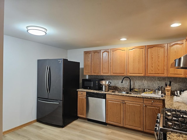 kitchen featuring gas range oven, stainless steel dishwasher, freestanding refrigerator, a sink, and black microwave