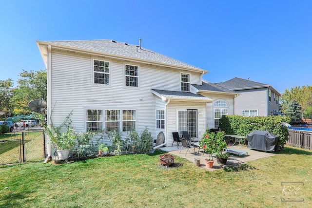 back of house featuring an outdoor fire pit, a shingled roof, fence, a yard, and a patio area