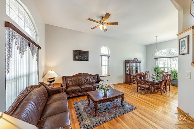 living area featuring light wood-type flooring, plenty of natural light, baseboards, and ceiling fan