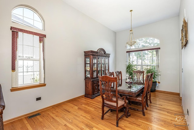 dining area featuring lofted ceiling, light wood-style flooring, visible vents, and baseboards