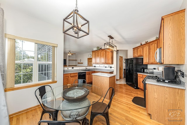 kitchen with black appliances, brown cabinets, a sink, and light wood finished floors