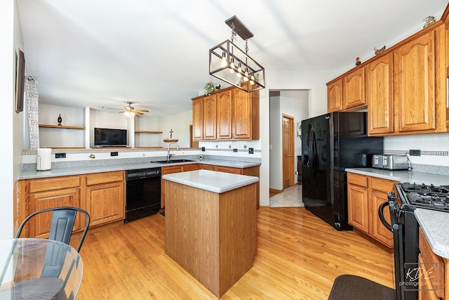 kitchen with light wood-style floors, a center island, a sink, and black appliances