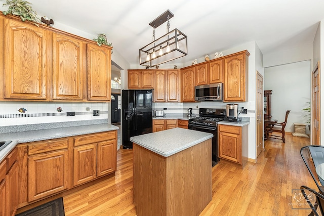 kitchen with a center island, light wood finished floors, light countertops, backsplash, and black appliances