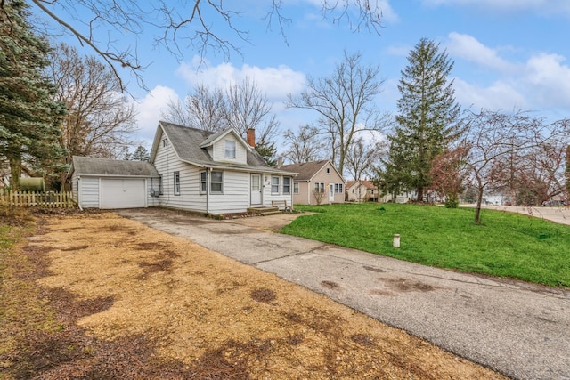 view of front facade featuring a front yard, a garage, and an outdoor structure