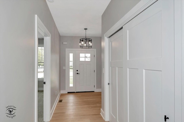 foyer entrance with light wood-type flooring and an inviting chandelier