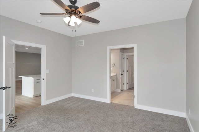 unfurnished bedroom featuring ceiling fan, ensuite bathroom, and light carpet