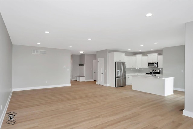 unfurnished living room featuring sink and light wood-type flooring