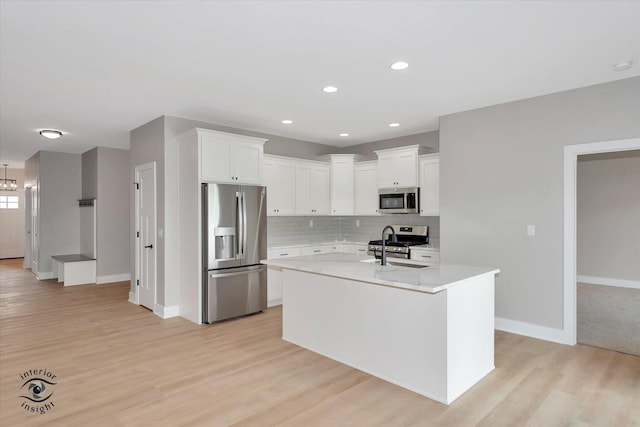 kitchen with a center island with sink, light hardwood / wood-style floors, white cabinetry, and appliances with stainless steel finishes