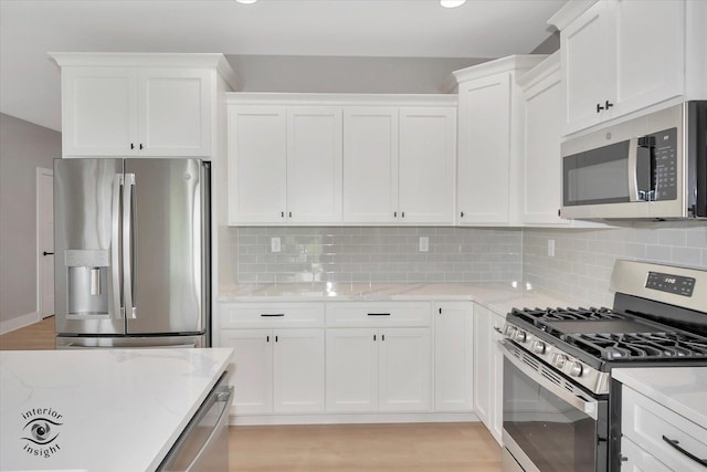 kitchen with backsplash, white cabinets, and stainless steel appliances