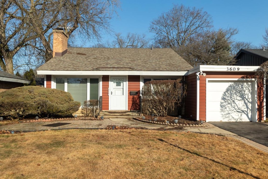 ranch-style home featuring a garage and a front lawn