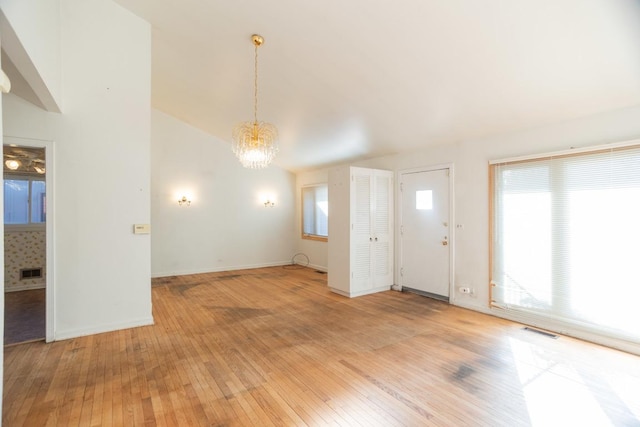 interior space featuring a notable chandelier, vaulted ceiling, and light wood-type flooring