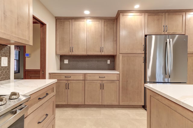 kitchen featuring backsplash, light stone counters, and stainless steel refrigerator