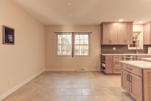 kitchen with decorative backsplash, light brown cabinetry, stainless steel dishwasher, sink, and light tile patterned floors