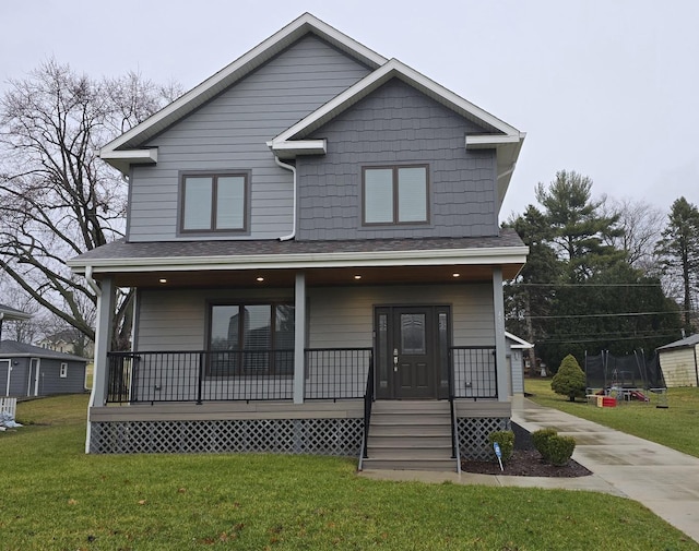 view of front of house with covered porch, a front yard, and a trampoline