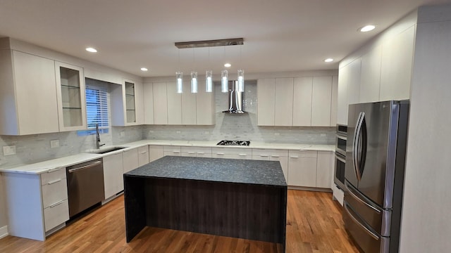 kitchen featuring white cabinetry, sink, a center island, decorative light fixtures, and appliances with stainless steel finishes