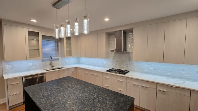 kitchen with sink, wall chimney exhaust hood, light stone countertops, light brown cabinetry, and a kitchen island