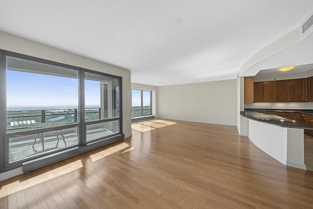 unfurnished living room with a water view and light hardwood / wood-style flooring