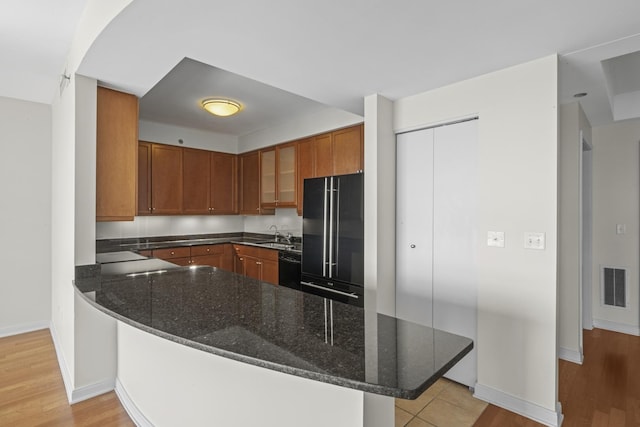 kitchen with a breakfast bar, dark stone counters, kitchen peninsula, and black appliances