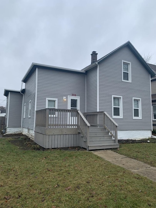 back of house with a deck and a lawn