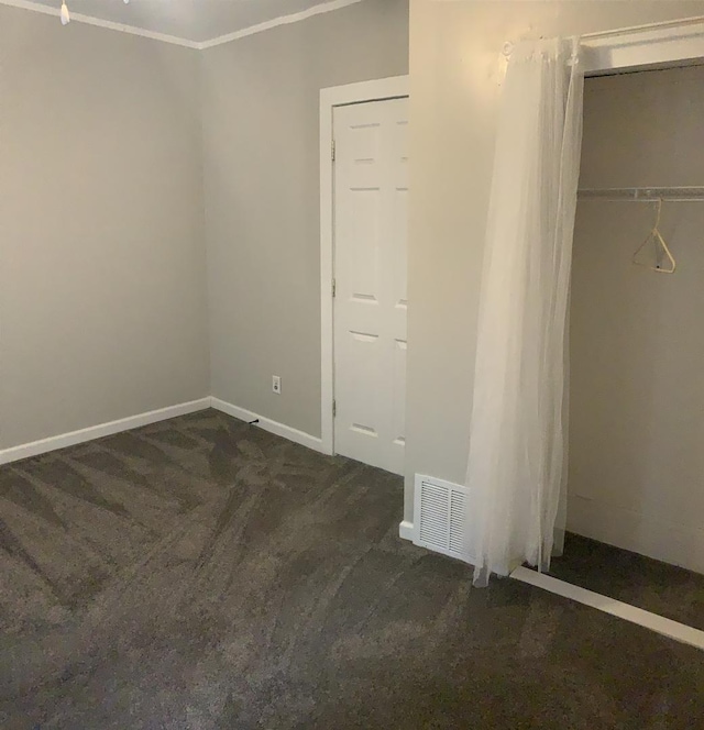 unfurnished bedroom with a closet and dark colored carpet