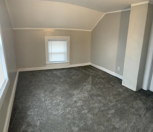 additional living space featuring dark carpet and vaulted ceiling