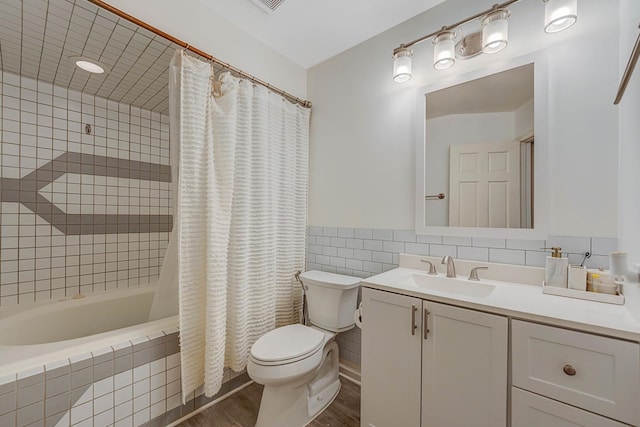 full bathroom featuring vanity, shower / bath combo with shower curtain, tile walls, hardwood / wood-style floors, and toilet