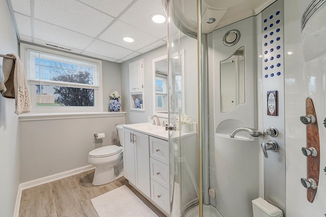 bathroom with hardwood / wood-style floors, a drop ceiling, vanity, toilet, and a shower with shower door