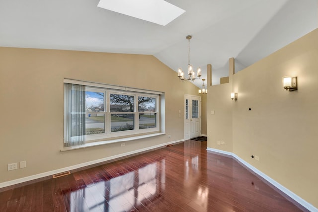 unfurnished dining area featuring lofted ceiling with skylight, wood-type flooring, and a notable chandelier