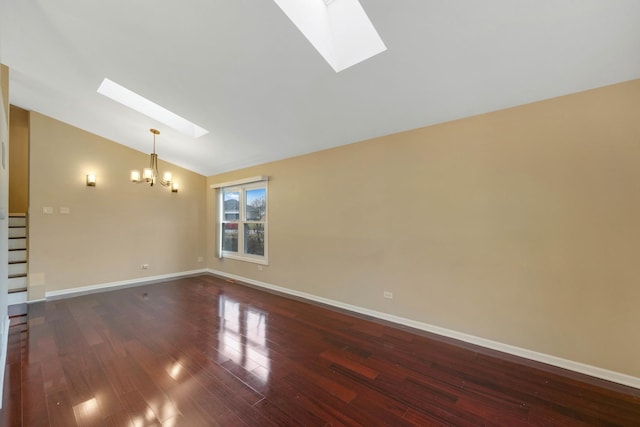 unfurnished room featuring lofted ceiling with skylight, dark wood-type flooring, and an inviting chandelier