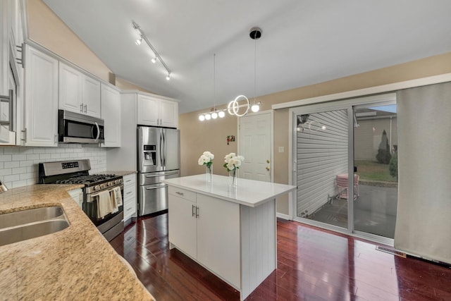 kitchen featuring a center island, tasteful backsplash, pendant lighting, white cabinets, and appliances with stainless steel finishes