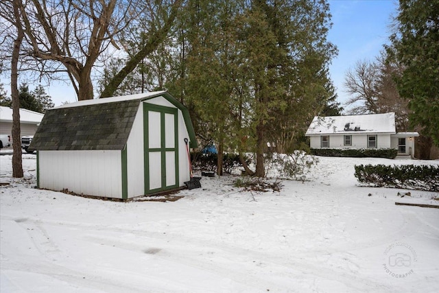 snowy yard featuring a storage unit