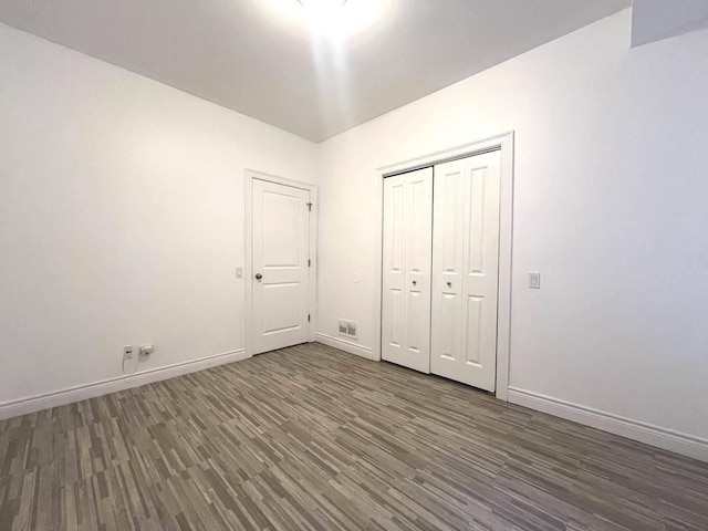 unfurnished bedroom featuring dark wood-type flooring and a closet