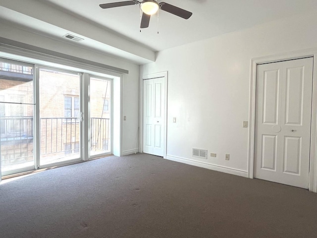 empty room featuring ceiling fan and dark carpet