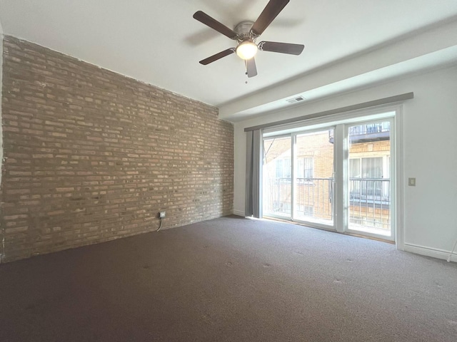 empty room with brick wall, carpet, and ceiling fan