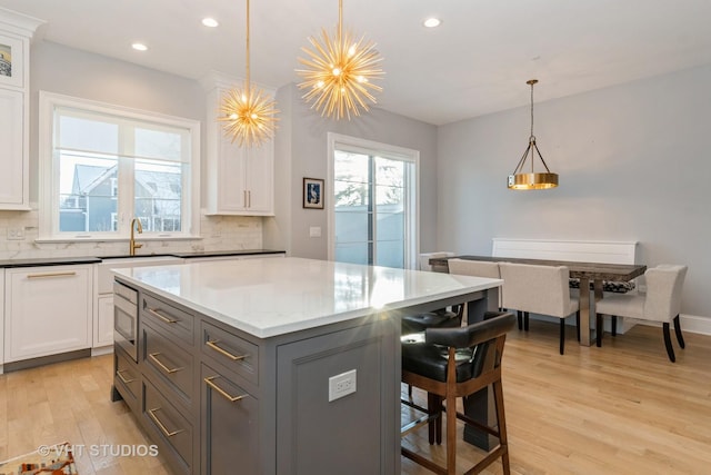 kitchen featuring white cabinets, backsplash, pendant lighting, and sink