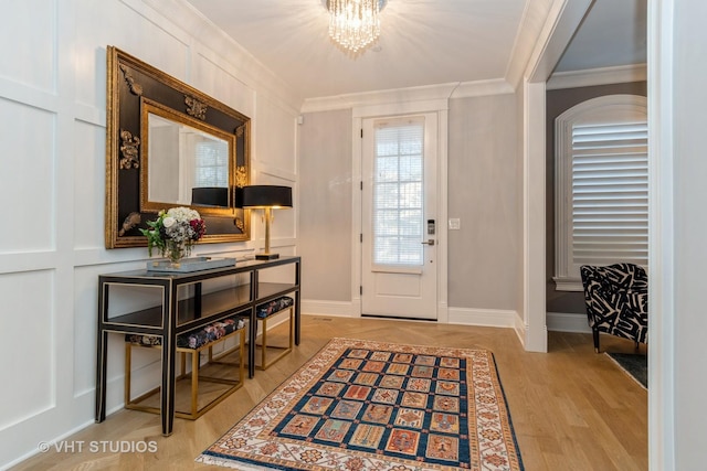 doorway with a notable chandelier, ornamental molding, and light wood-type flooring